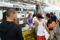 Besucher des Afrikafests am Infostand der Amnesty-Gruppe Ingolstadt.